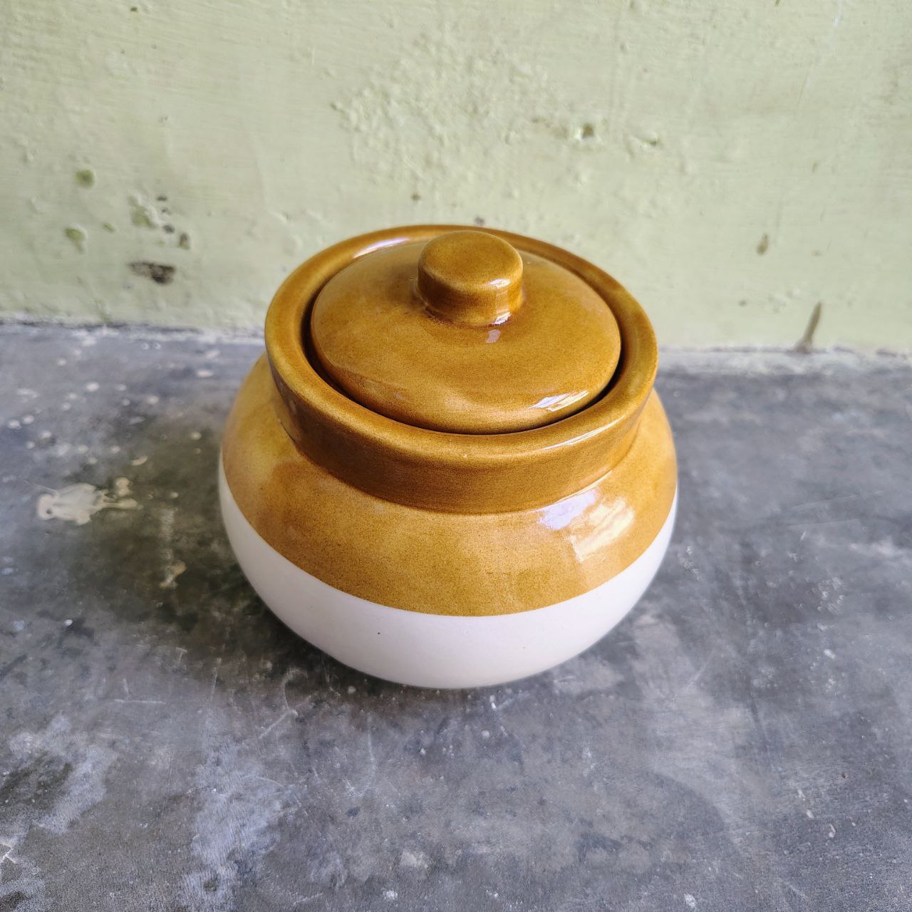 Open brown white ceramic pickle jar with lid kept aside top angle