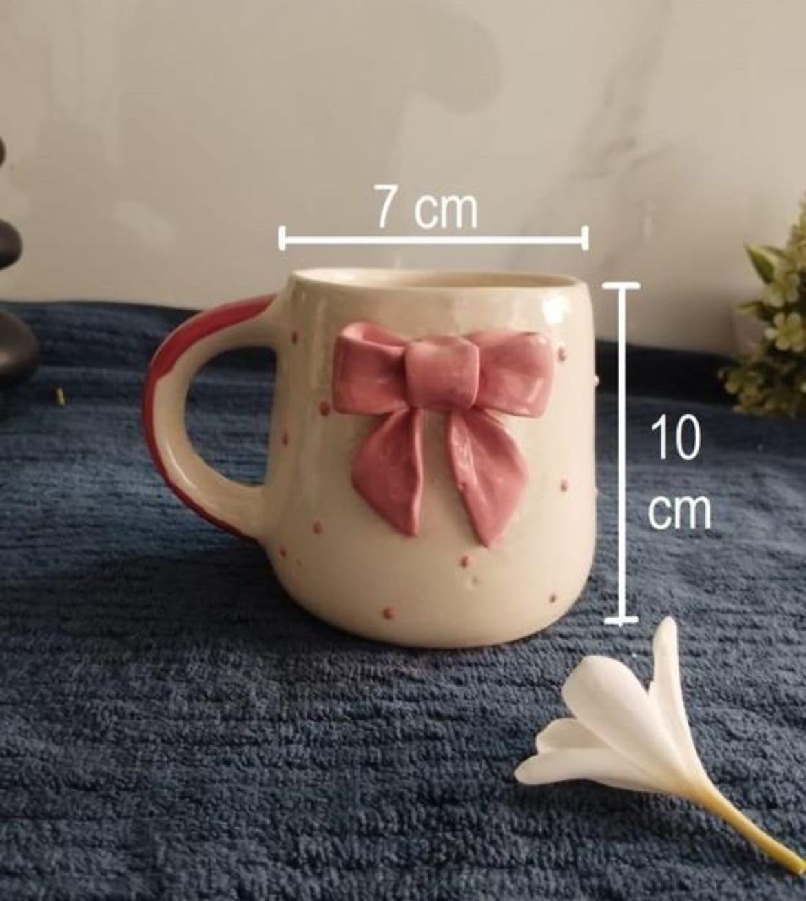 High-resolution close-up of glossy ceramic mug featuring sculpted pink ribbon