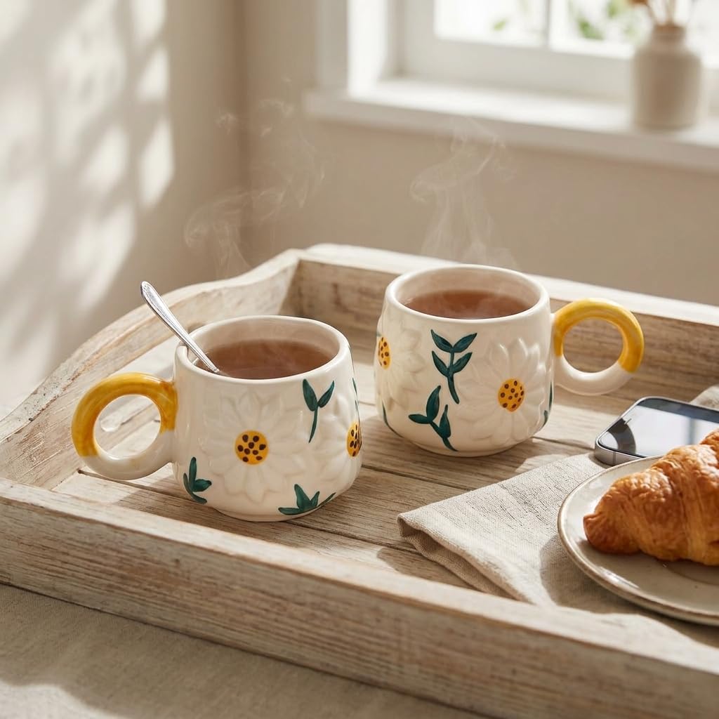 Two matching 3D daisy flower ceramic cups served with fresh croissants on wooden breakfast tray